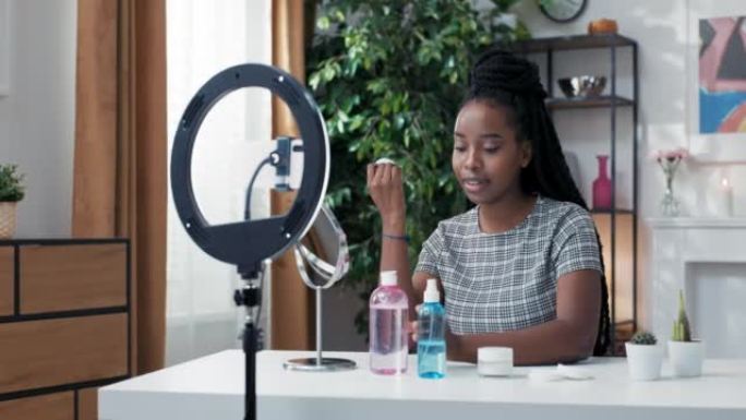 女性影响者在社交媒体上记录了她的护肤程序的vlog。一个皮肤黝黑的女孩服用棉球和卸妆液。关于如何正确