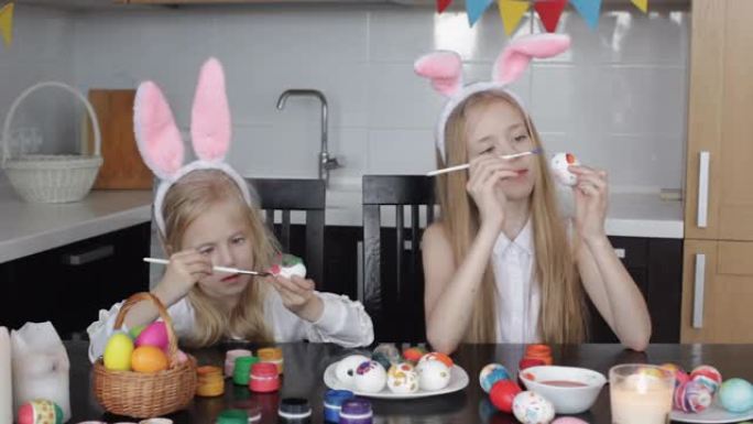 两个兔耳朵的小女孩正在画复活节彩蛋，孩子们正在为春节假期做准备，