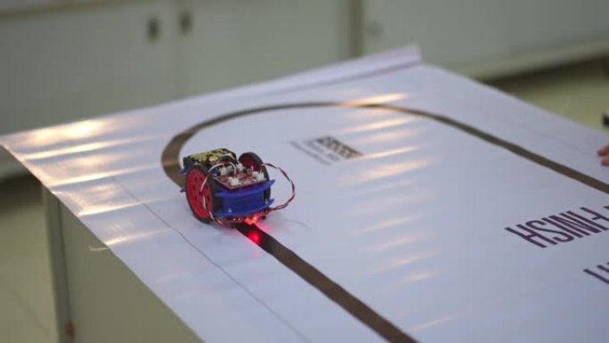 在实验室中测试在路线上运行的具有传感器响应的机器人机器人汽车。建筑师设计电路和会议共享技术思想和协作