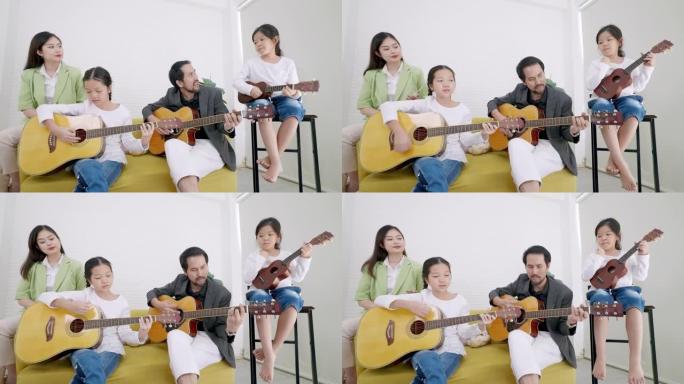 高级教师和初级亚洲女孩坐在音乐工作室的沙发上弹吉他，美丽的亚洲年轻教师唱着这首歌，另一个初级亚洲女孩