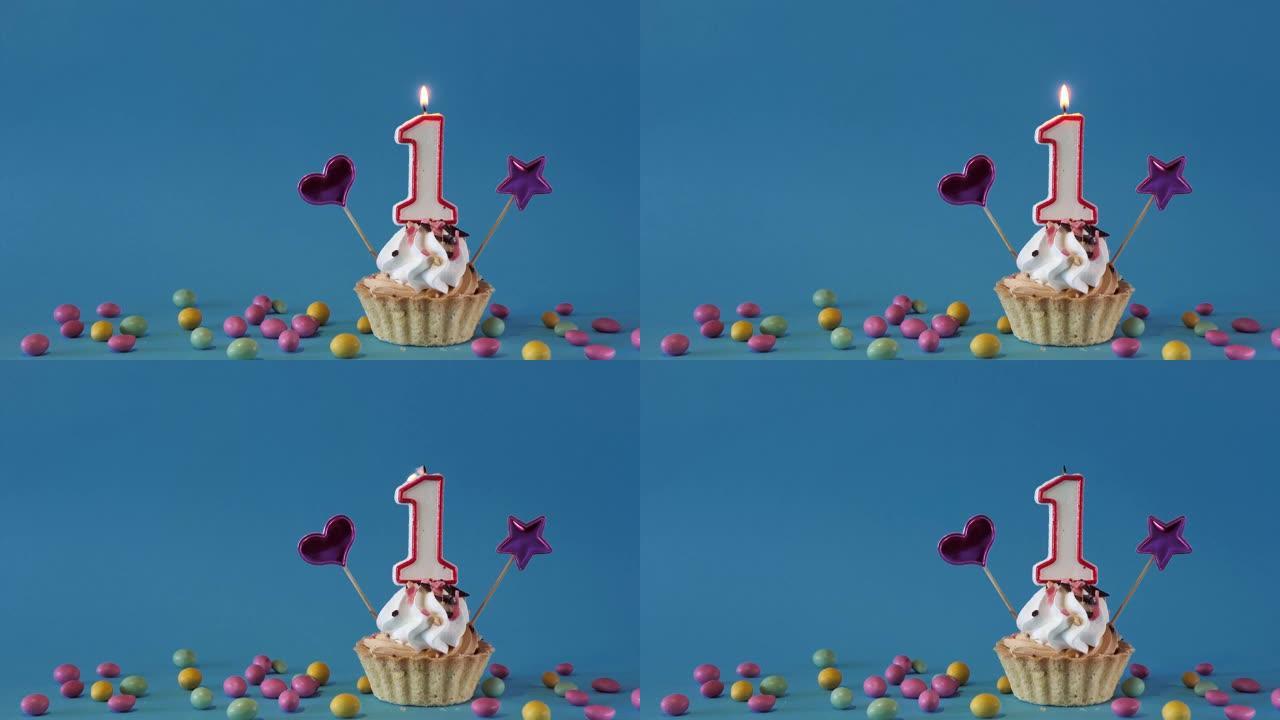 祝1岁宝宝生日快乐，带蜡烛的生日蛋糕和蓝色背景上的生日装饰品。复制空间