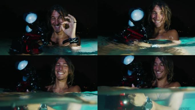 夜间水下摄影。坐在水中的快乐男性水下摄影师的肖像