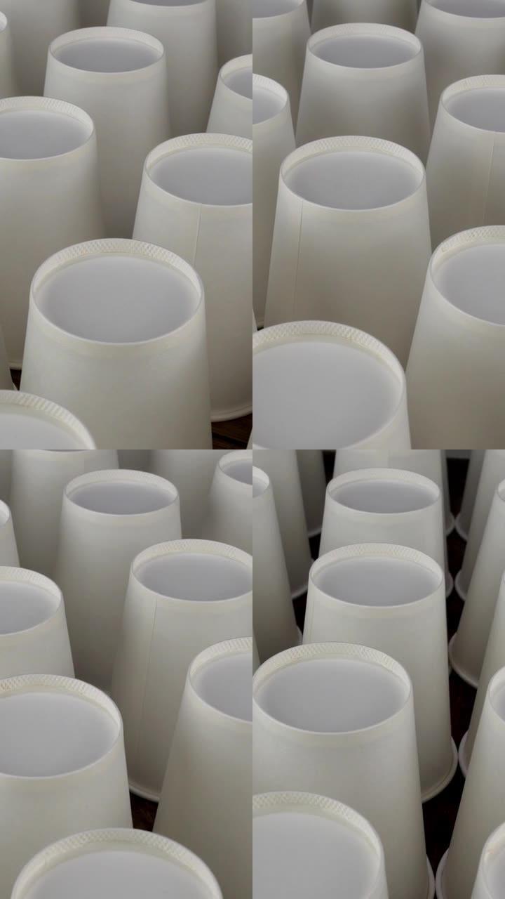 一排白色一次性纸杯在黑暗的背景下缓慢旋转，用于咖啡或热饮料。