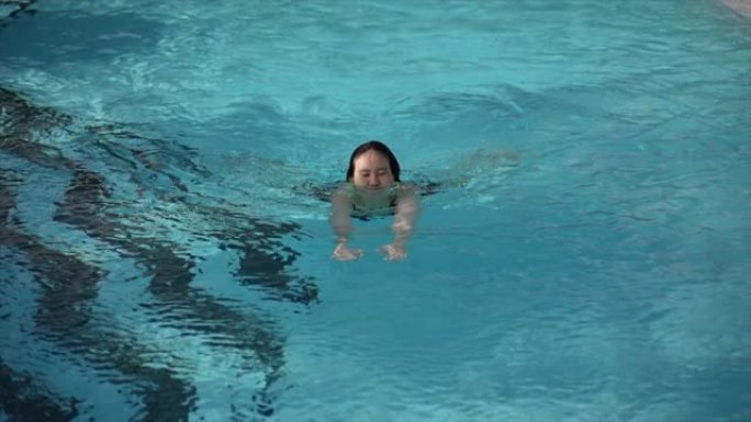 夏季的亚洲女性在游泳池里游泳
