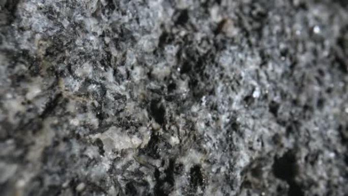 灰色粗糙花岗岩天然石材纹理背景。黑色工作室背景上有纹理图案的一块石头。建筑用矿物石材。地质、矿石、资