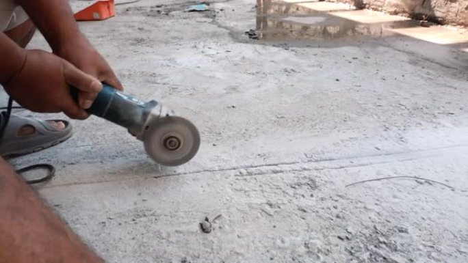 用磨床用电锯切割混凝土地板铺设电线的工人手的特写