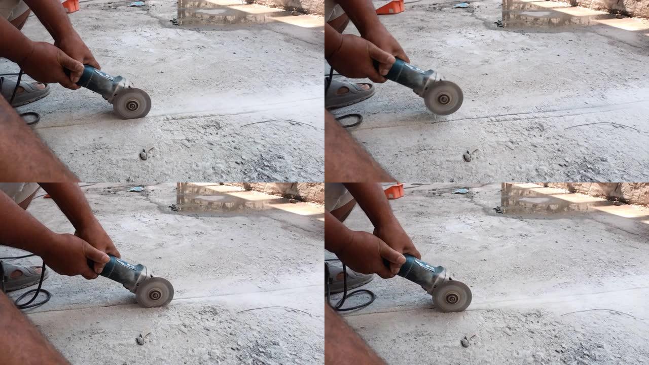 用磨床用电锯切割混凝土地板铺设电线的工人手的特写
