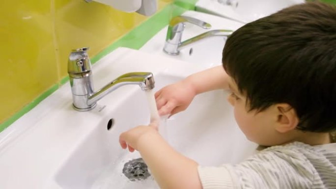 一个4岁的小男孩自己用水龙头洗手