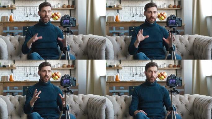 受欢迎的博主男子在家用专业相机拍摄新的vlog视频。男性内容创作者坐在沙发上拍摄在线课程。用摄像机录