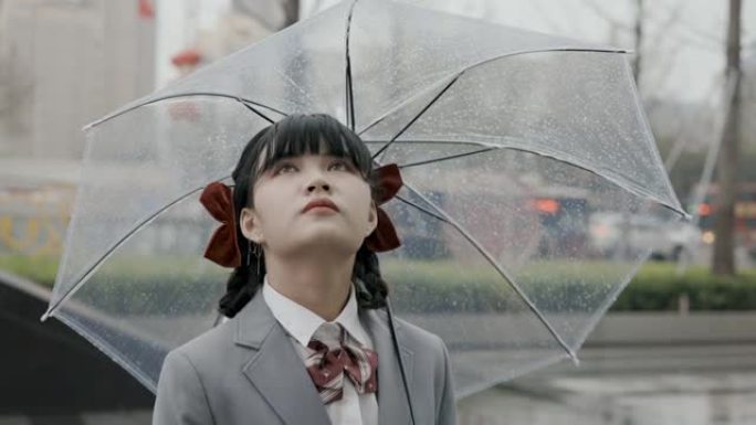 日本女学生身穿校服站在雨中手持透明雨伞