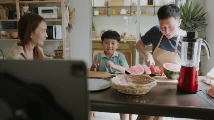 亚洲男孩在家里直播制作新鲜西瓜冰沙时与他的追随者交谈。