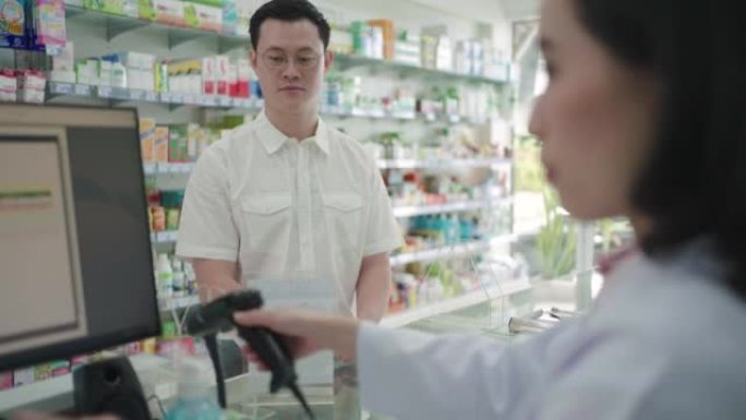 亚洲男子客户扫描付款二维码在药房购买药物。