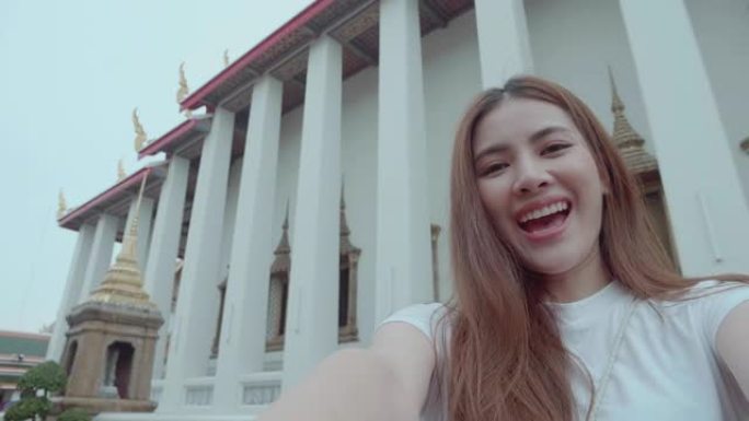 泰国曼谷的大皇宫和Wat Pho是一位美丽的年轻女性影响者享受和幸福的视角直播。后视图是意外拍摄的地
