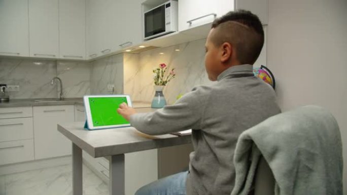 男生在室内通过平板电脑在线做功课的后视图