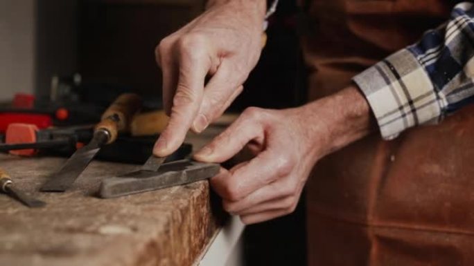 木匠磨凿子。木工车间用手工工具进行木工加工。木雕概念。高质量4k镜头