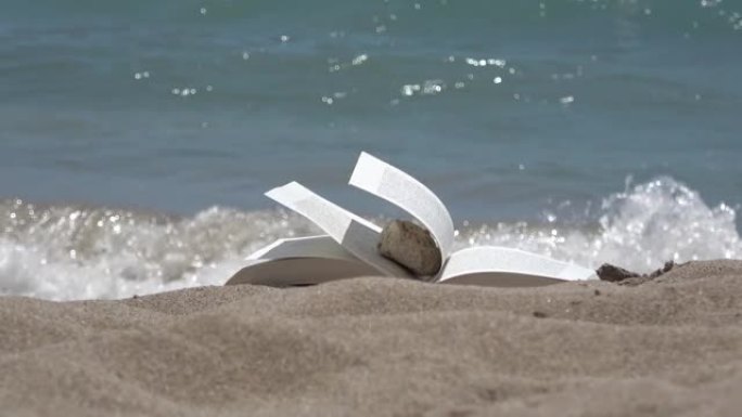 在夏日海滩上随风飘扬的书。镜头