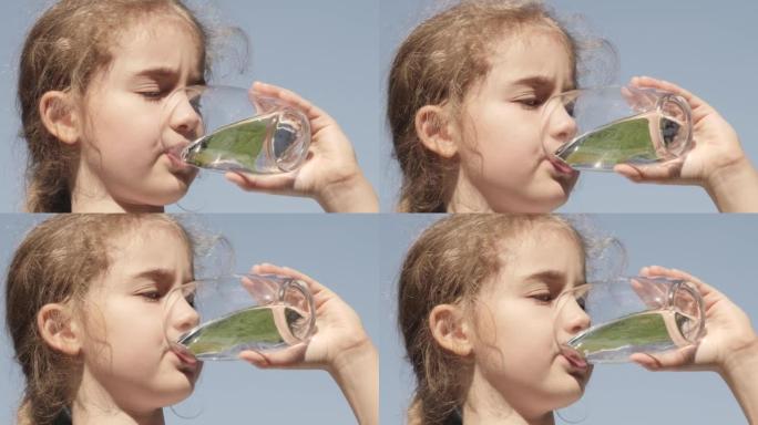 可爱女孩饮杯新鲜透明纯过滤水慢动作儿童饮杯水健康身体护理健康生活方式。口渴的孩子在户外用玻璃喝水，阳