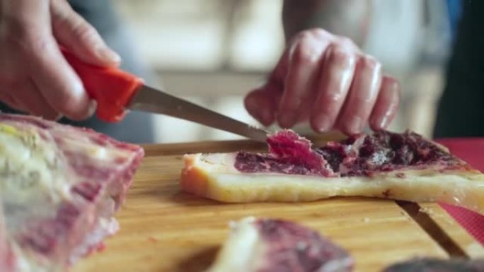 干牛里脊放在木板上，屠夫用锋利的刀子切成优质的肉干牛排，用于餐饮服务。豪华餐厅的熏肉牛排，bilto