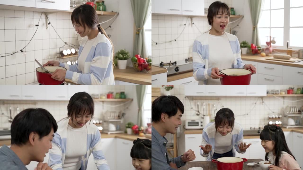 快乐的亚洲妈妈为丈夫和女儿准备食物的慢动作。她在餐桌上端上一锅汤，用手扇风享受美味的气味