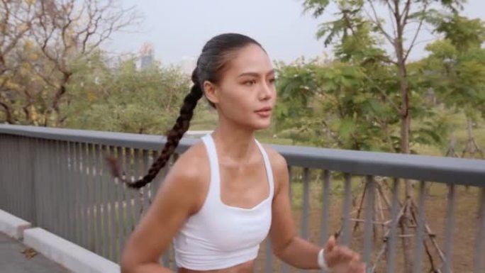 年轻的健身女性穿着运动服在城市公园慢跑，健康生活方式。
