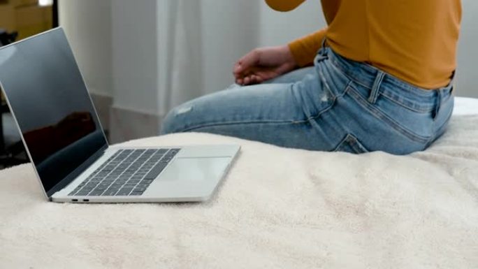 4K 50fps，一名身穿黄色长袖衬衫的亚洲女子，坐在白色床上，旁边放着一台笔记本电脑，焦急地将手机