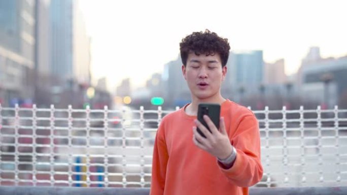 RT/亚洲年轻帅哥正在城市街道上使用智能手机