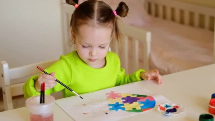一个可爱的小女孩将刷子浸入一杯水中，并用水粉仔细地描绘了自己的图画。一个孩子学会画画。一个孩子从拼图