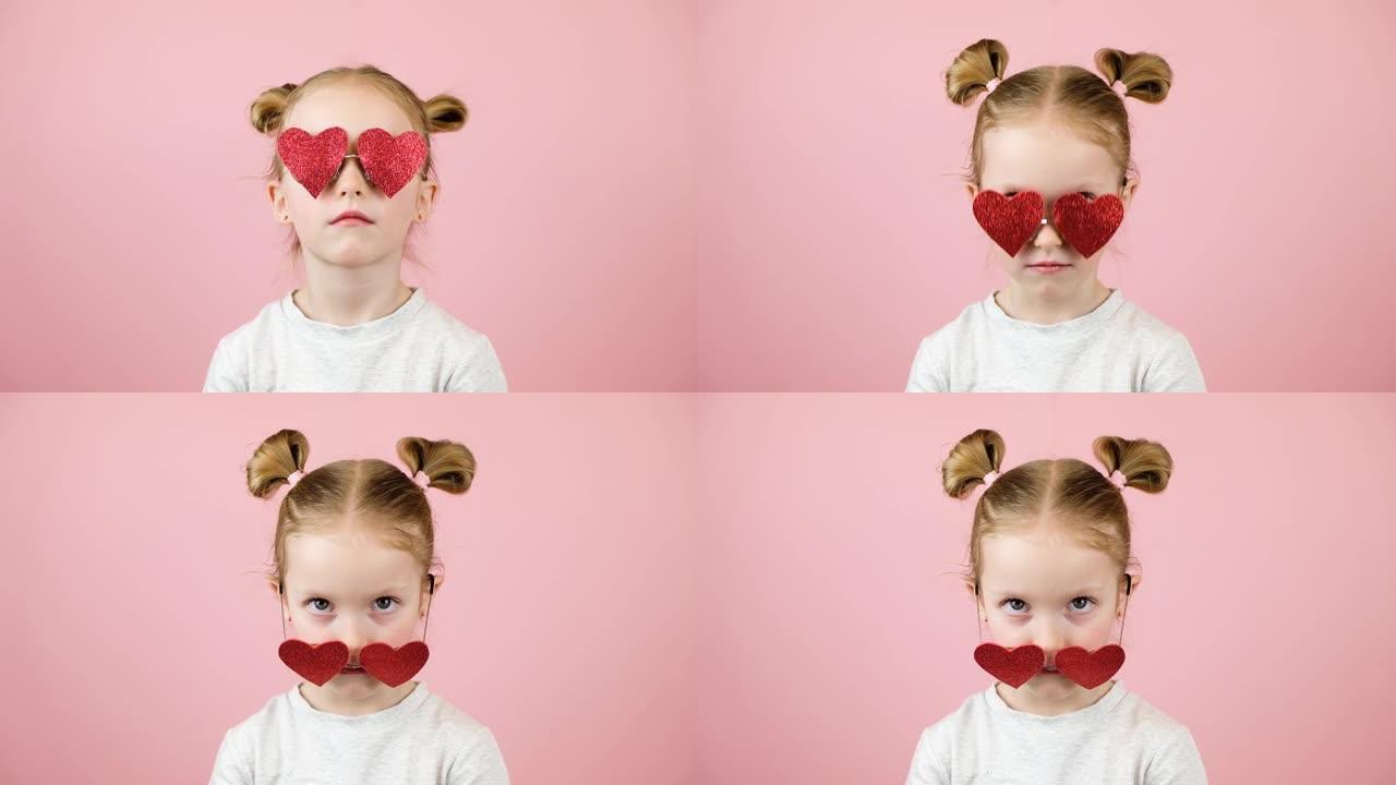 有趣的金发小女孩微笑着玩粉色背景的红色心形太阳镜。情人节或母亲节概念