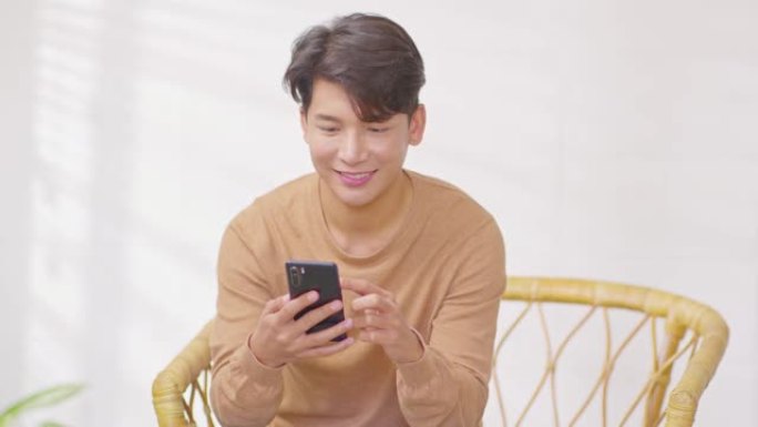 幸福企业家英俊的商业亚洲年轻人穿休闲用手机购物在线享受社交媒体和笔记本电脑在家。小企业创业。网上银行