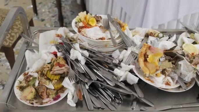 宴会上的剩菜。服务员用手推车收集脏盘子。很多脏盘子。