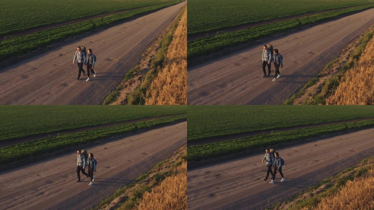 搭便车的人和旅行者，一个带着女孩的年轻人，背着背包沿着黑麦和小麦播种的谷物田行走。
