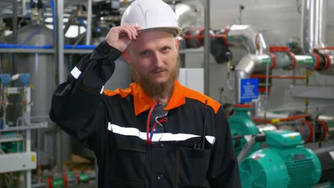 制造厂的工业工程师。一个戴着白色安全帽和工作服的大胡子男人在工作场所。在油气加工厂的油气结构中工作