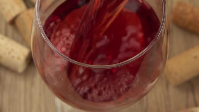 将葡萄酒倒入酒瓶塞背景的玻璃杯中。