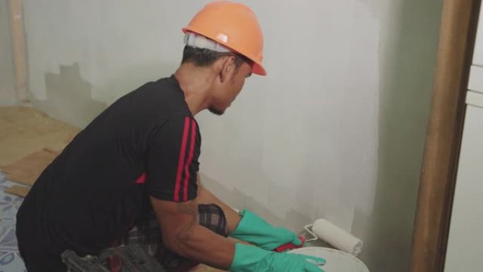 亚洲男子在家画墙刷油漆大白墙刮腻子
