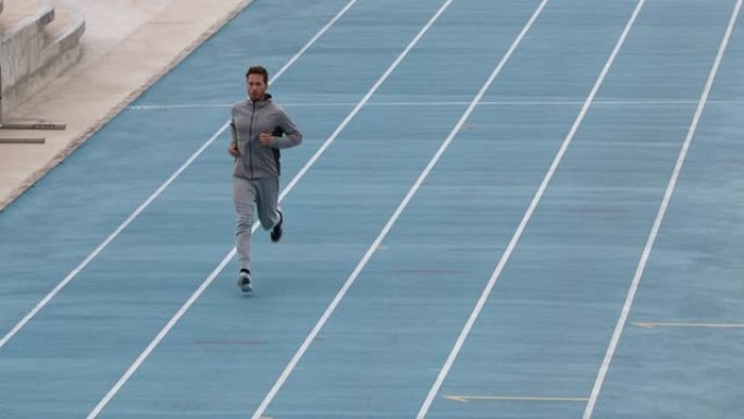 田径田径体育场跑步训练。男运动员穿着运动服慢跑热身。跑步运动概念。以59.94 FPS拍摄慢动作。