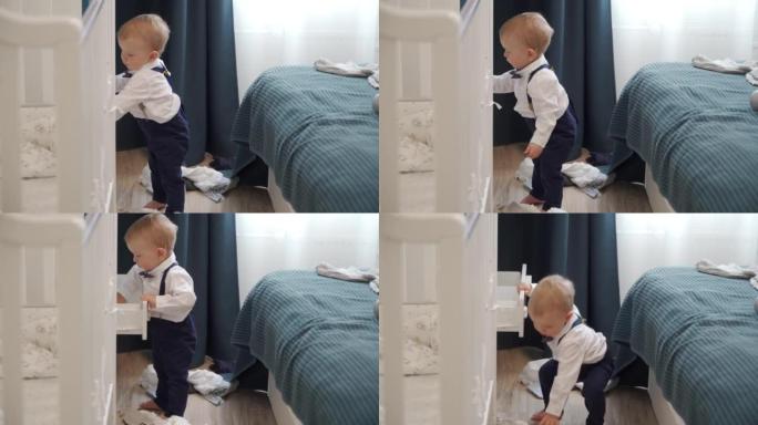 蹒跚学步的孩子用衣服探索衣柜的抽屉，一岁的男婴将衣服从壁橱中拉出并扔到地板上。