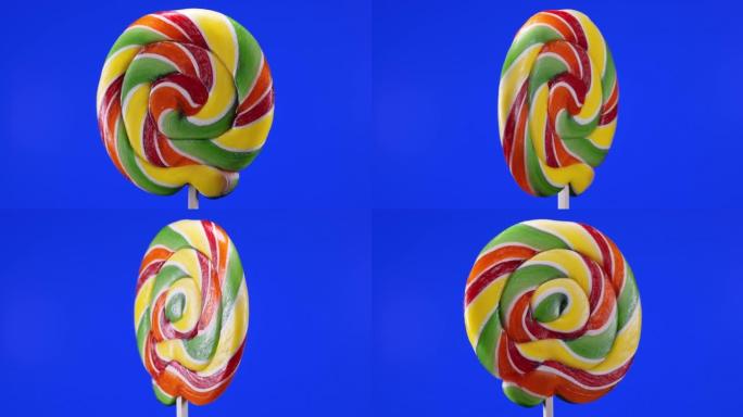 蓝色背景上螺旋水果棒棒糖的旋转。焦糖棒棒糖。儿童糖果。宏观。童年概念。