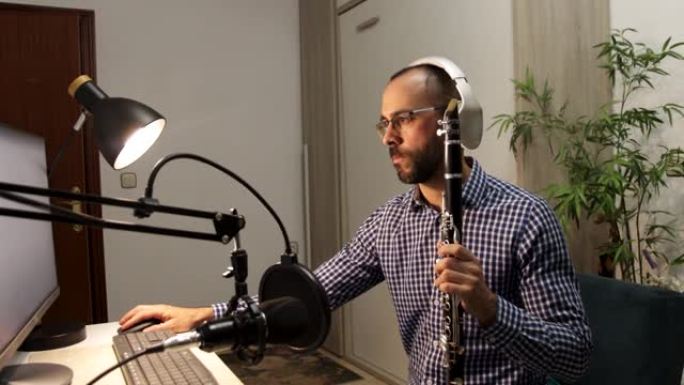年轻的企业家在家里演奏单簧管，并录制音乐，用他的电脑在线播放