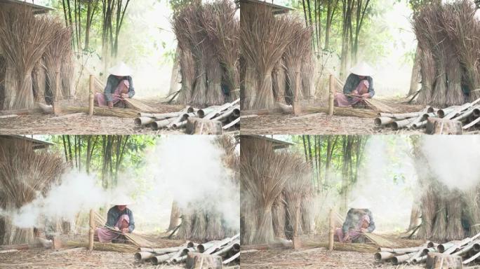 亚洲生活老奶奶在户外工作。老太太老人严重生活在泰国农村的农村。编织材料草屋顶毛边竹制。