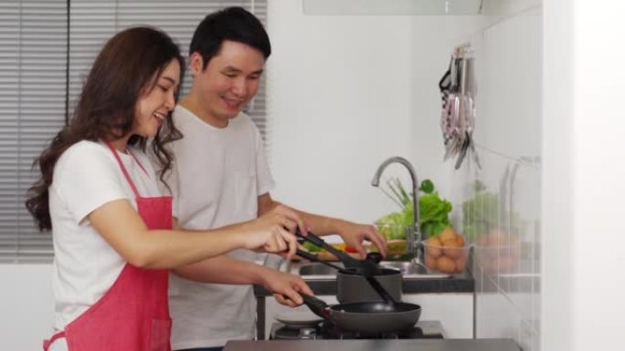 幸福的年轻夫妇在家里的厨房里做饭和准备食物