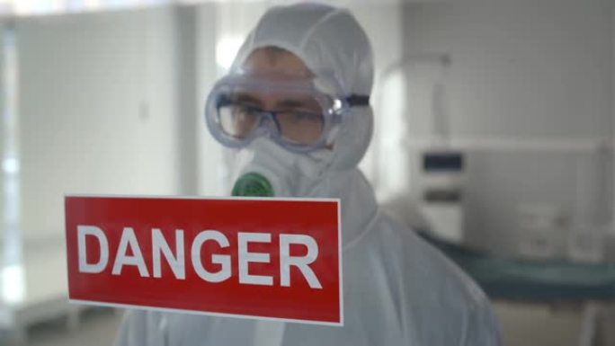 身穿危险品服的医务人员在医院玻璃门上贴上危险标志