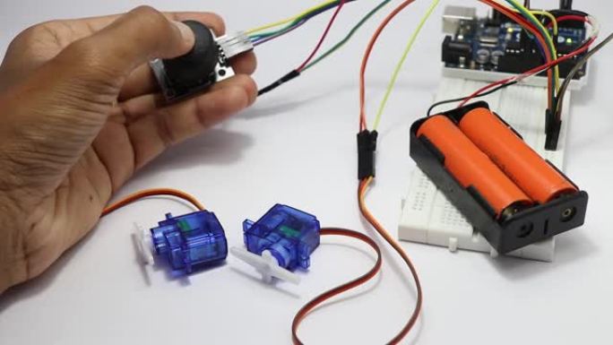 拇指操纵杆模块控制原型电子电路中的微型伺服系统，显示了实验室中一位年轻发明家的一些测试