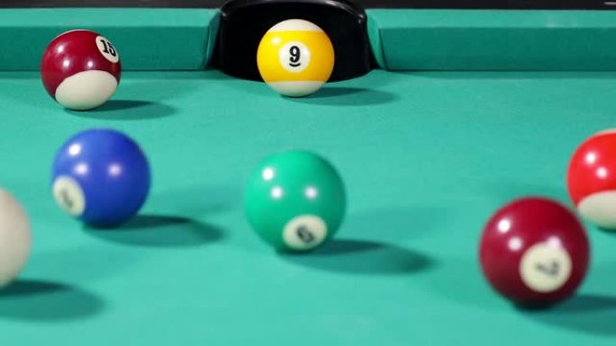 黄色台球的特写镜头被桌子上的蓝色和白色球击中后进入洞中