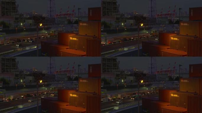黄昏的货物起重机集装箱码头。东京有交通的高速公路。