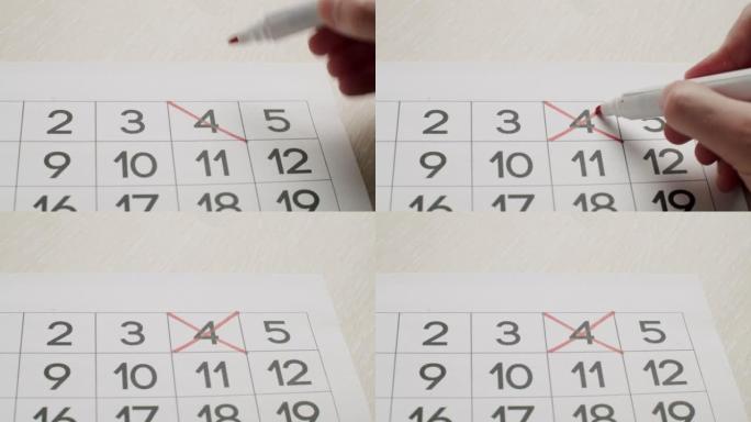 人的手用红笔在纸质日历上写下第4天。