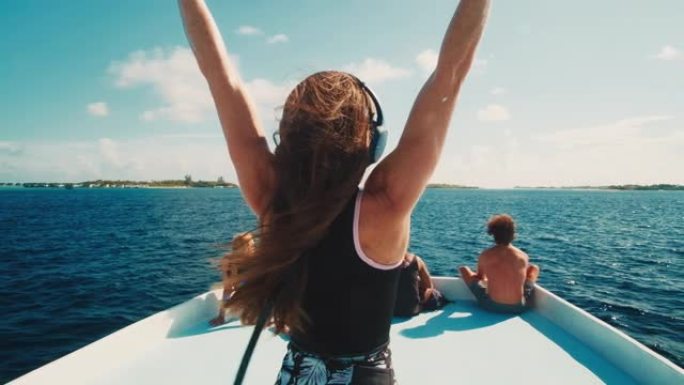 快乐的女人戴着耳机在移动的船顶上跳舞