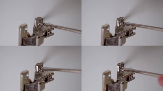 螺丝刀拧紧门铰链的自攻螺钉。特写选择性聚焦