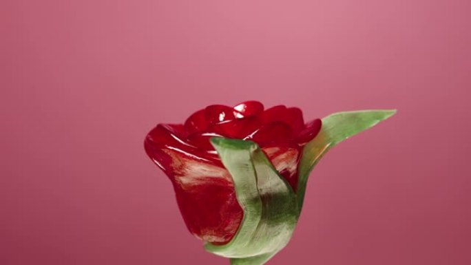 在粉红色背景上旋转的红色玫瑰花形式的棒棒糖。带有水果味的甜糖果。棒棒糖。儿童生日的糖甜点。慢动作就绪