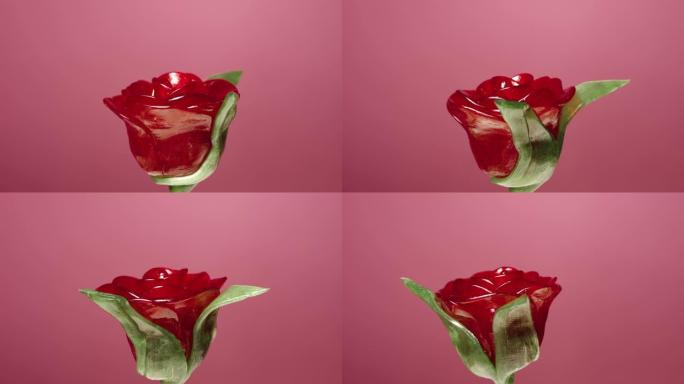 在粉红色背景上旋转的红色玫瑰花形式的棒棒糖。带有水果味的甜糖果。棒棒糖。儿童生日的糖甜点。慢动作就绪