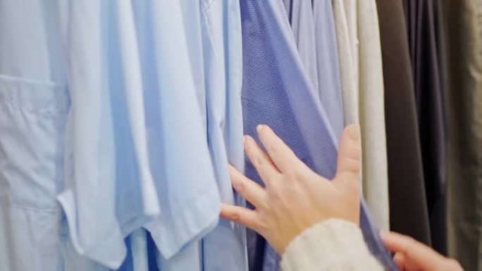 女性双手特写整理蓝色衣架上的男式衬衫